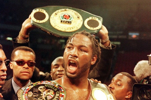 Lennox Lewis celebrates with championship belts after winning a boxing match.